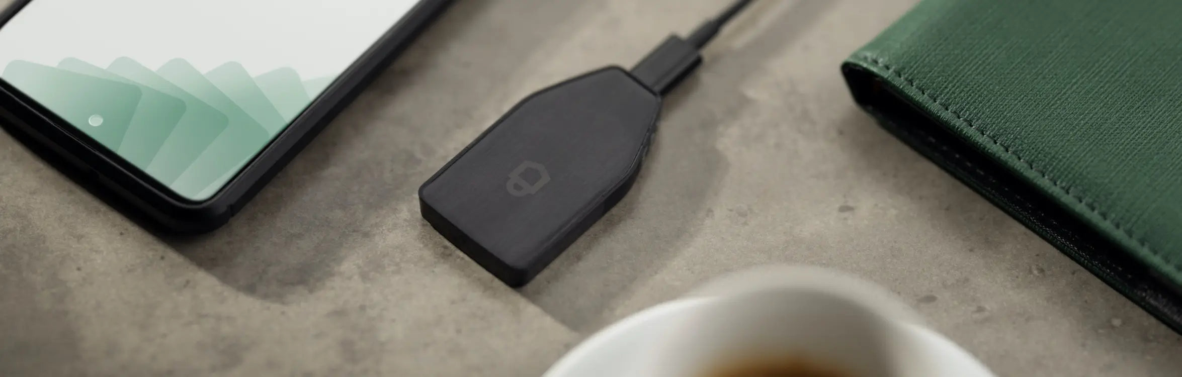 Trezor Safe 3 cold wallet facedown on a surface next to a laptop and a coffee.