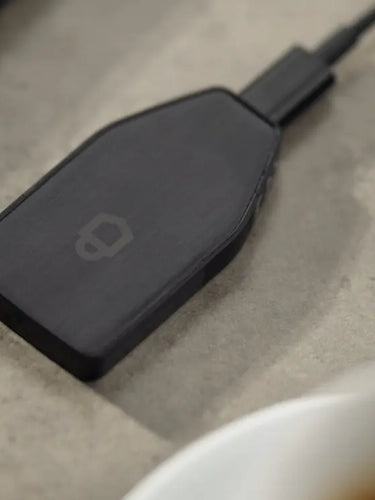 Trezor Safe 3 cold wallet facedown on a surface next to a laptop and a coffee.
