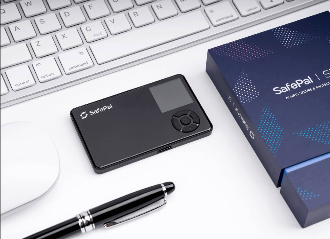 A SafePal S1 hardware wallet face up on a computer desk with a pen, a mouse and a keyboard next to it.